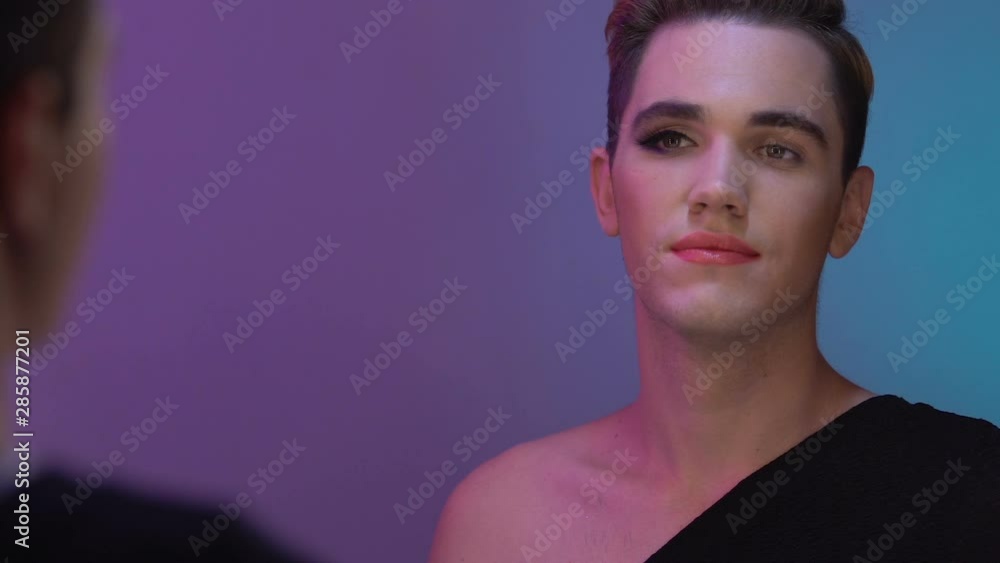 Bisexual man with half-face make up looking mirror, male and female gender Bisexual man with half-face make up looking mirror, male and female gender