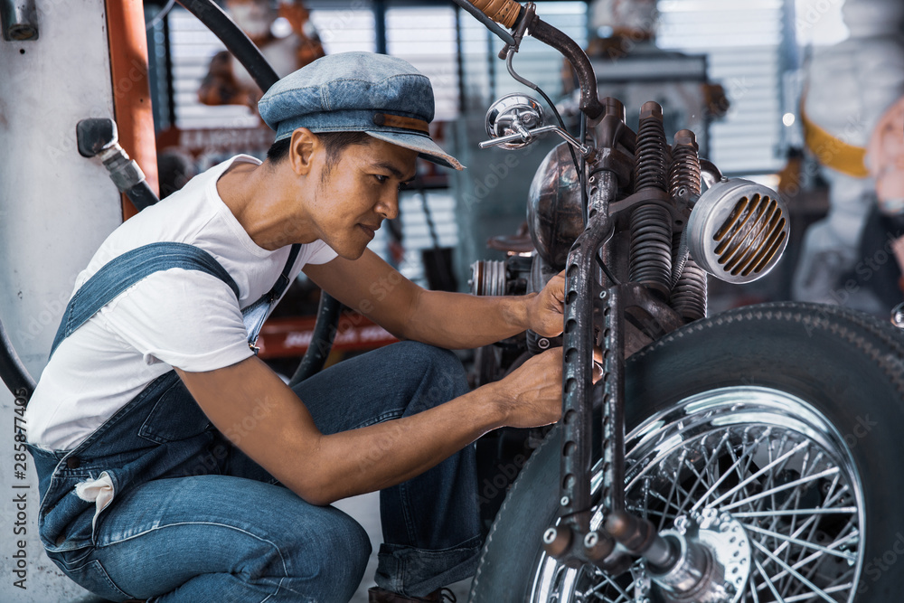 Mechanical technician man maintenance and repair motorbike at workshop, vintage moto style