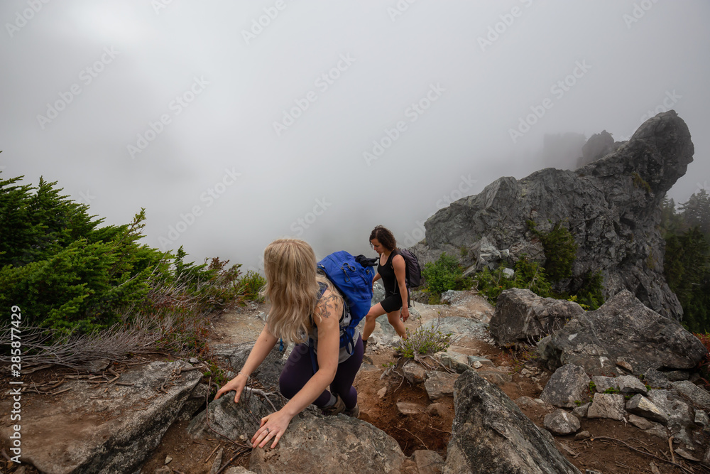Adventurous Girl is hiking up a steep trail up a beautiful rocky mountain during a cloudy summer morning. Taken on Crown Mountain, North Vancouver, BC, Canada.