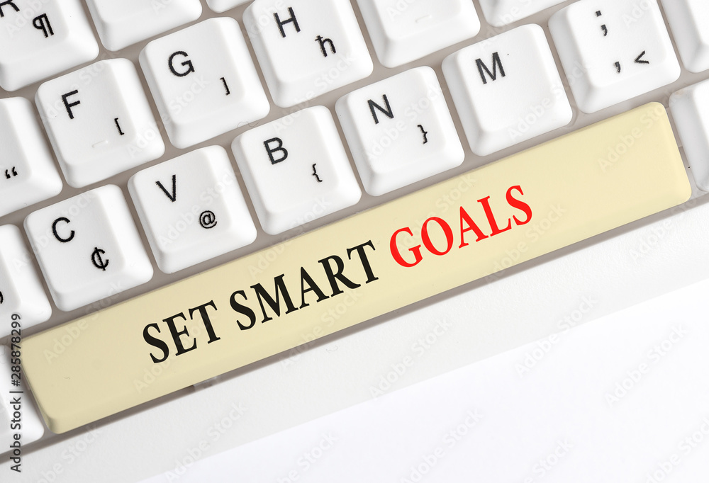 Writing note showing Set Smart Goals. Business concept for giving criteria to guide in the setting of objectives White pc keyboard with note paper above the white background Writing note showing Set Smart Goals. Business concept for giving criteria to guide in the setting of objectives White pc keyboard with note paper above the white background