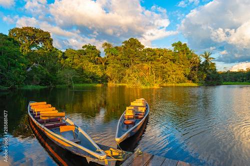 Two traditional wooden canoes at sunset in the Amazon River Basin with the tropical rainforest in the background inside the Yasuni National Park, Ecuador, South America. photo