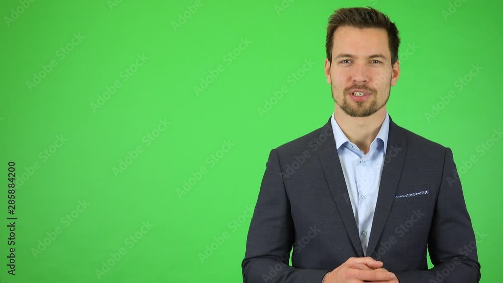A young handsome businessman talks to the camera with a smile - green screen studio