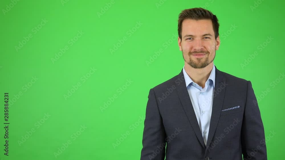 A young handsome businessman walks into the frame and smiles at the camera - green screen studio A young handsome businessman walks into the frame and smiles at the camera - green screen studio