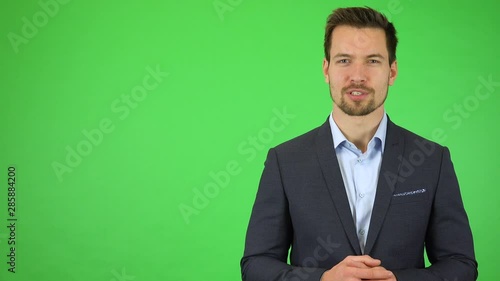 A young handsome businessman talks to the camera with a smile - green screen studio