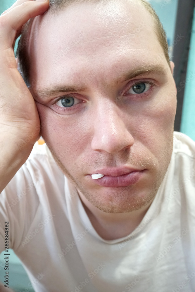 blond man with a sick look and a pill in his mouth blond man with a sick look and a pill in his mouth