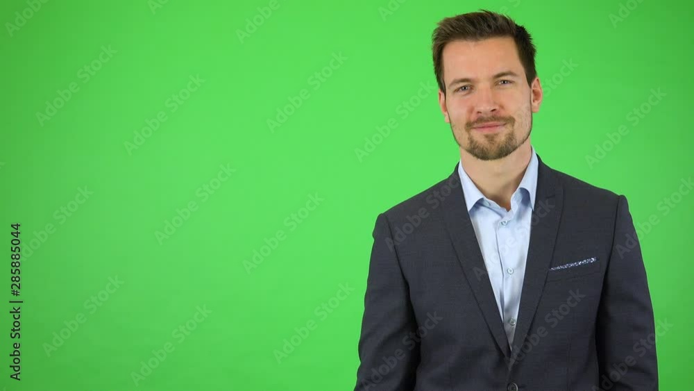 A young handsome businessman presses an invisible button in front of him and smiles at the camera - green screen studio A young handsome businessman presses an invisible button in front of him and smiles at the camera - green screen studio
