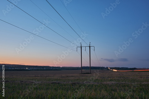 High-voltage power lines at sunset passing through the field. Power line
