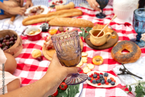 Hold glass with juice at picnic blanket background