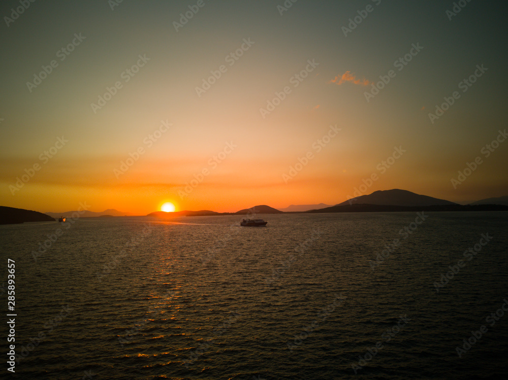 Sunset on the water in greece and boats and ferries