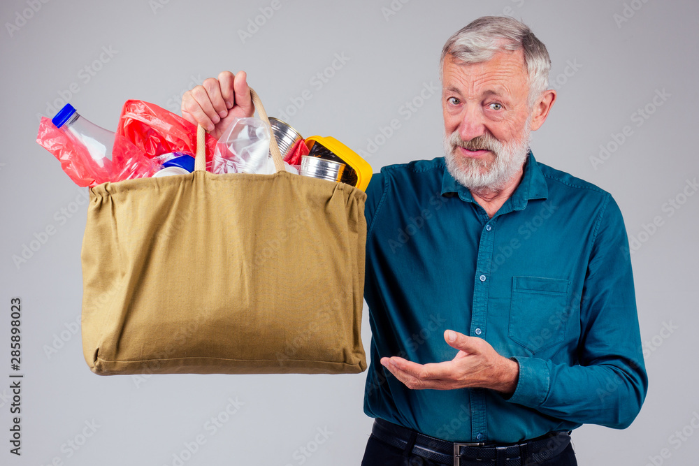 old grandfather holding cotton eco bag full of garbage in studio white background old grandfather holding cotton eco bag full of garbage in studio white background