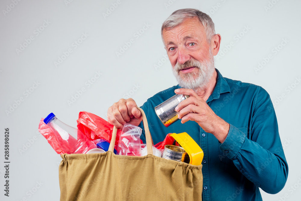 old grandfather holding cotton eco bag full of garbage in studio white background old grandfather holding cotton eco bag full of garbage in studio white background