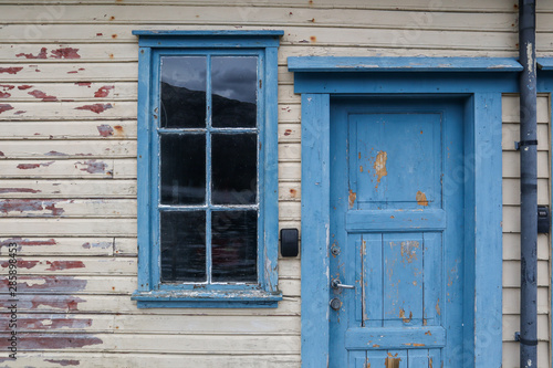 Window with a blue frame and a blue wooden door in a wooden wall