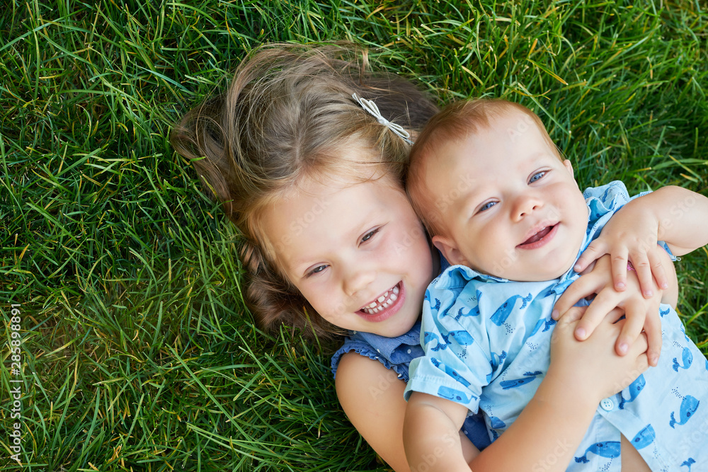children sister with brother in the park on the grass children sister with brother in the park on the grass