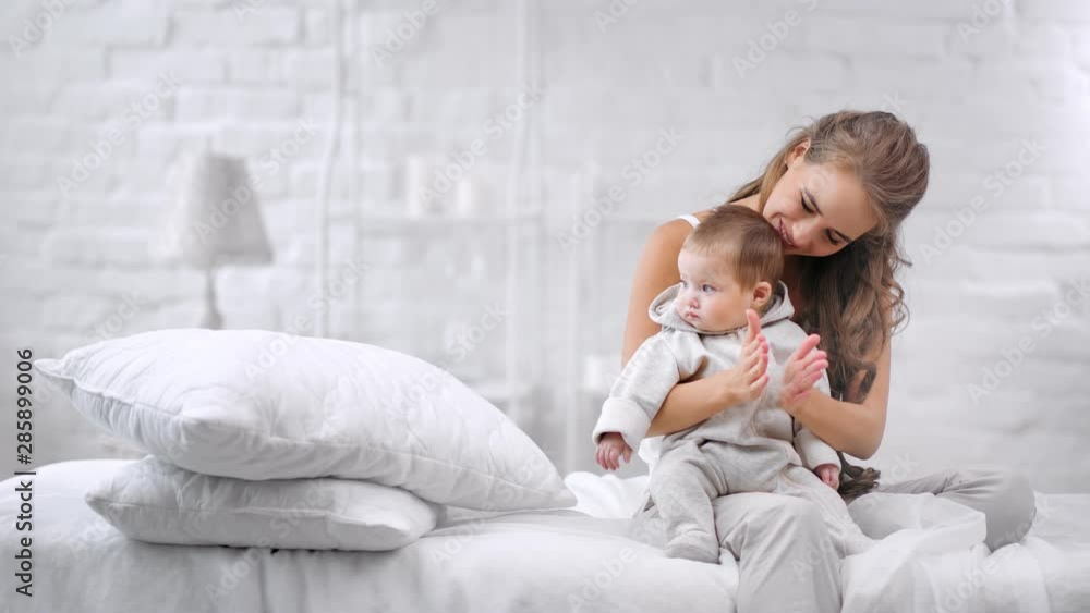 Adorable smiling young mother playing with little cute baby clapping hand feeling tenderness Adorable smiling young mother playing with little cute baby clapping hand feeling tenderness