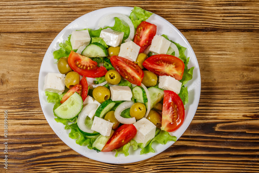 Greek salad with fresh vegetables, feta cheese and green olives on wooden table. Top view Greek salad with fresh vegetables, feta cheese and green olives on wooden table. Top view