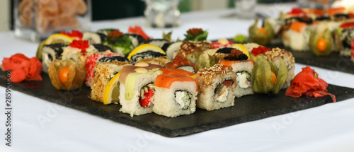 Set of sushi rolls with vasabi and ginger on a dark slate plate, Buffet table, horizontal orientation, close up