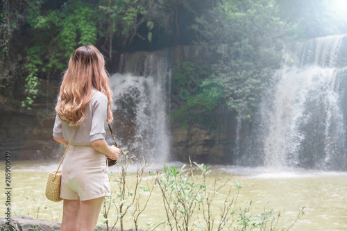 Young woman traveler travel into amazing beautiful waterfalls in tropical forest