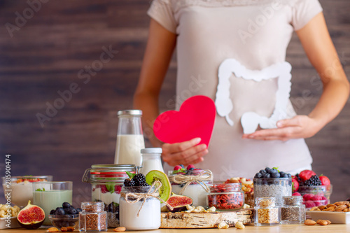 Female is holding figures of heart and intestines. Summer breakfast with organic yogurts fruits, berries and nuts. Nutrition that promotes good digestion and functioning of gastrointestinal tract.