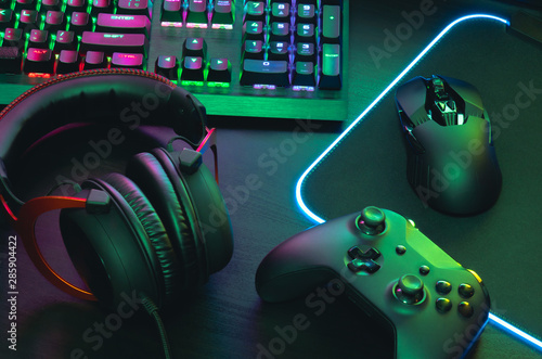 gamer work space concept, top view a gaming gear, mouse, keyboard, joystick, headset, mobile joystick, in ear headphone and mouse pad on black table background. photo