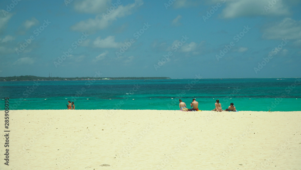 Tropical beach with tourists and clear blue sea. Summer and travel vacation concept. Daco, Philippines