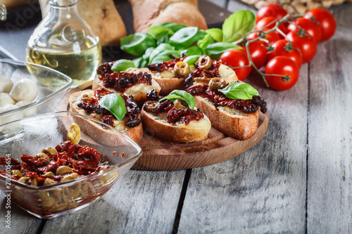 Appetizer bruschetta with sun-dried tomatoes, olives and mozarella.