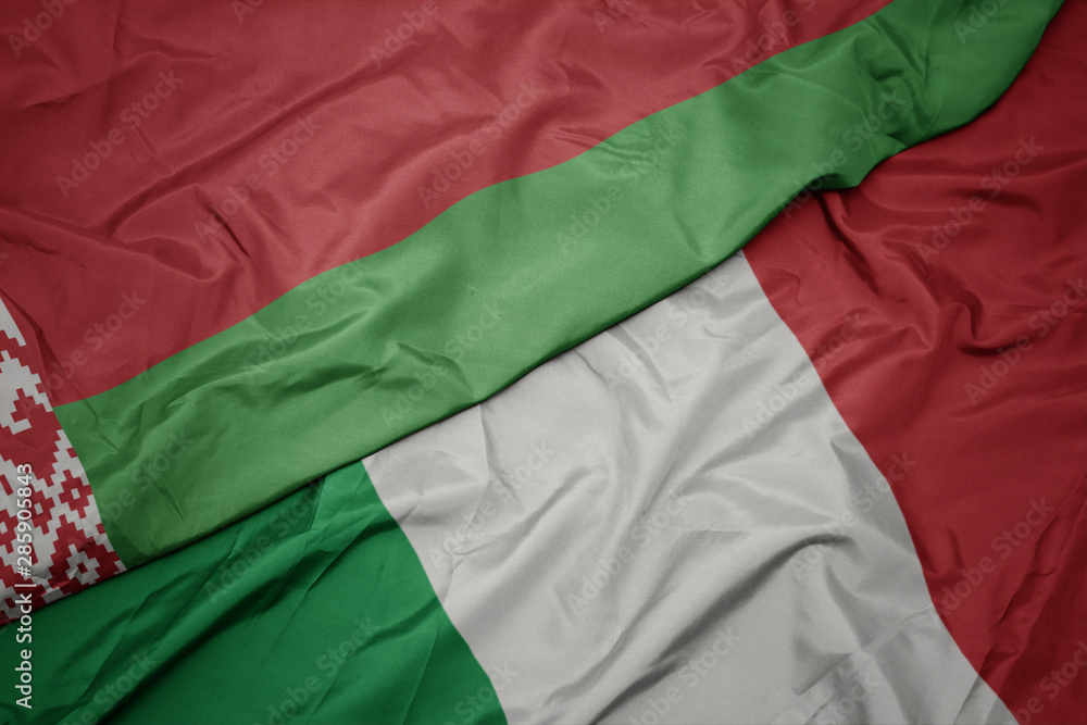 waving colorful flag of italy and national flag of belarus.
