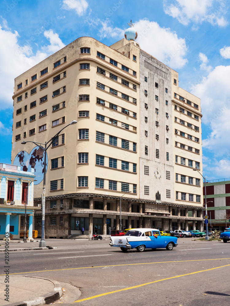 Old masonry building in Habana and colorful vintage cars, Havana, Cuba.