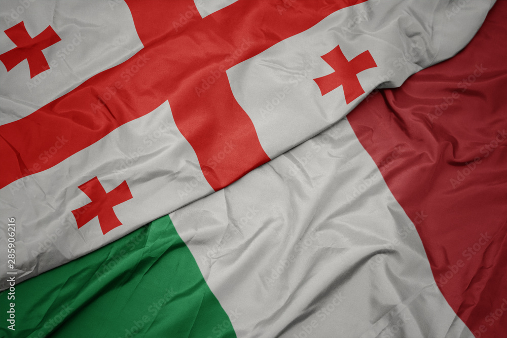 Fototapeta premium waving colorful flag of italy and national flag of georgia.