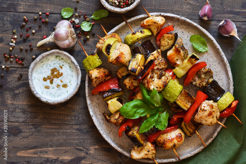 Grilled chicken fillet and vegetables. Barbecue of chicken on skewers with vegetables on wooden background. Picnic.