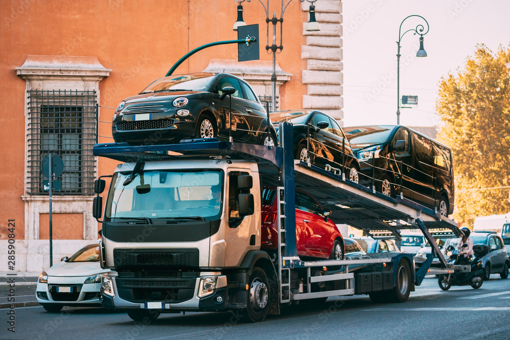 Fototapeta premium Auto-transport Carrying New Fiat Cars In European City Street. Auto Transport Broker Or Car Transporter