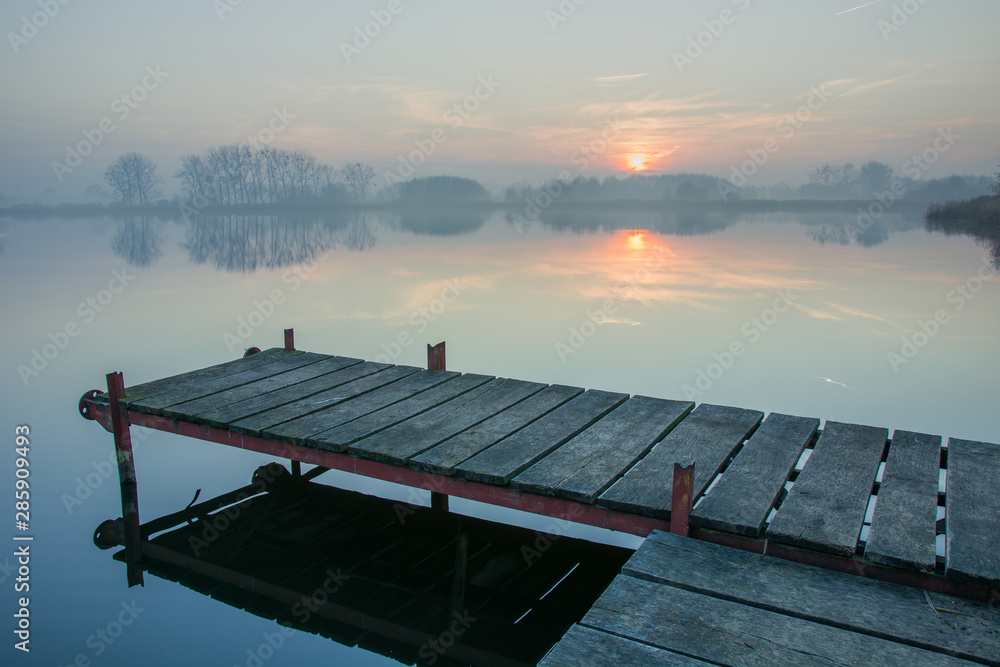 Jetty from a board, sunset over a misty lake