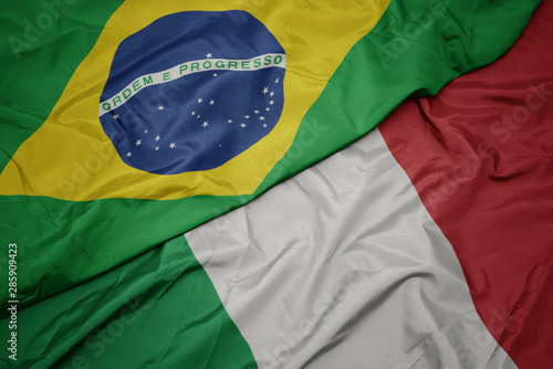 waving colorful flag of italy and national flag of brazil.