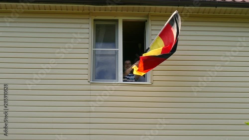 Young people waving a flag in a window at home photo