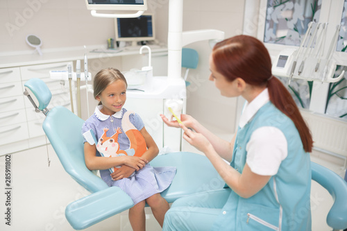 Top view of girl looking at dentist telling about teeth