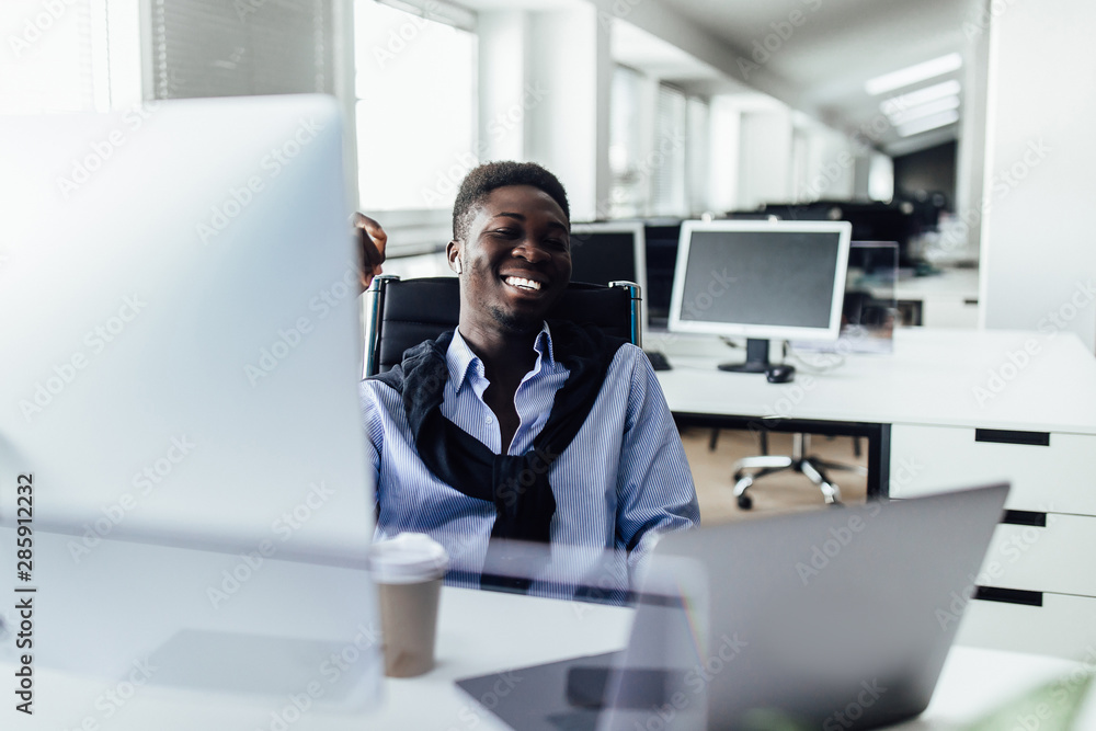 Attractive positive , with candid emotions American office worker sitting at desk in front of open laptop pc and making notes.