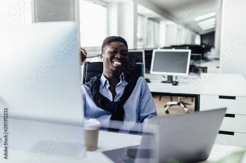 Obraz na płótnie Attractive positive , with candid emotions American office worker sitting at desk in front of open laptop pc and making notes. w salonie