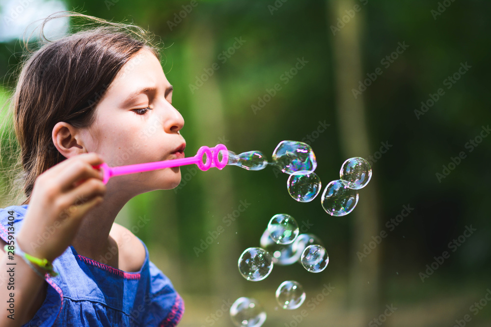 happy beautiful girl blowing soap bubbles outdoor