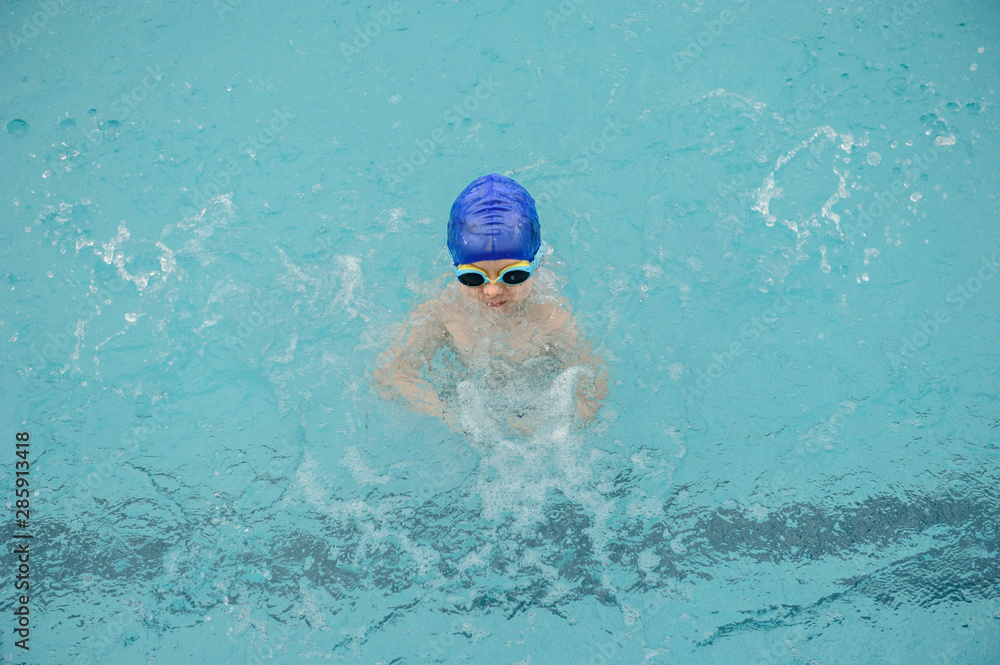 top view of a 7-year boy playing and swimming in the swimming pool