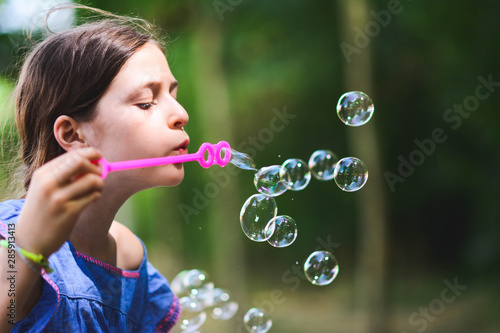 happy beautiful girl blowing soap bubbles outdoor