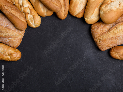 Copy space with different types of bread on black background