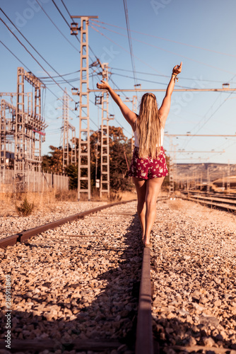 Young blonde girl walking along the train tracks