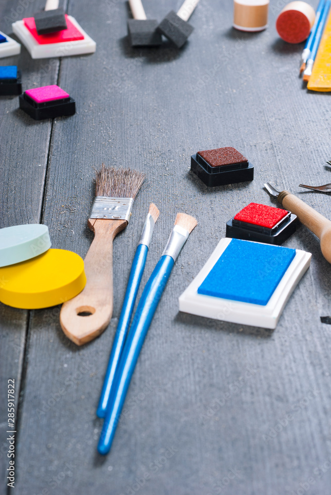ink pads, plasticine blocks, brushes, paint roller and carving cutters on black wood table ink pads, plasticine blocks, brushes, paint roller and carving cutters on black wood table