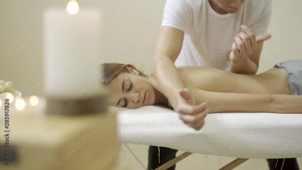 Beautiful young woman relaxing with massage. Strong man arms on her back. Beautiful young woman relaxing with massage. Strong man arms on her back.