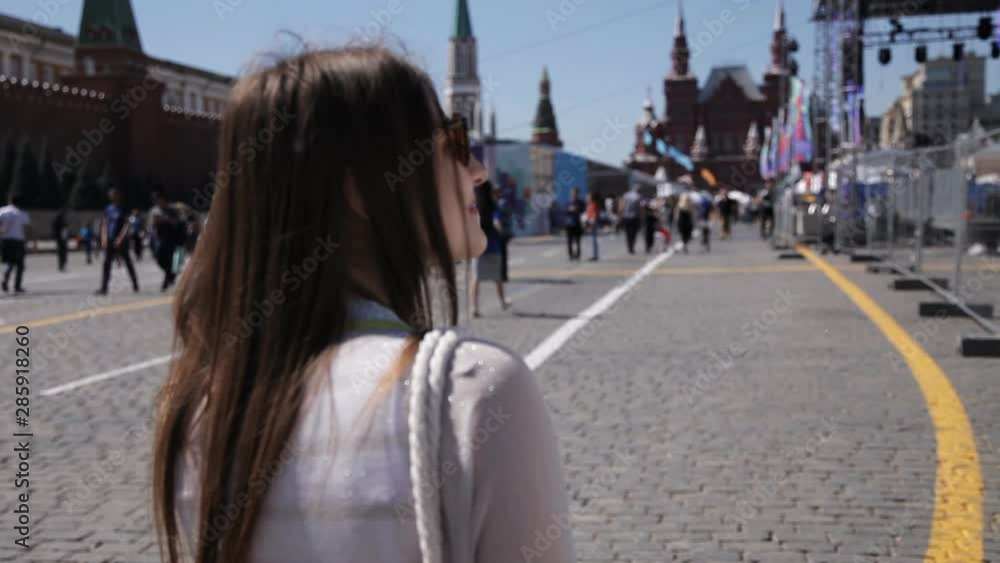 A girl walks around the square in sunny weather, a crowd of people pass by. Tourism concept A girl walks around the square in sunny weather, a crowd of people pass by. Tourism concept