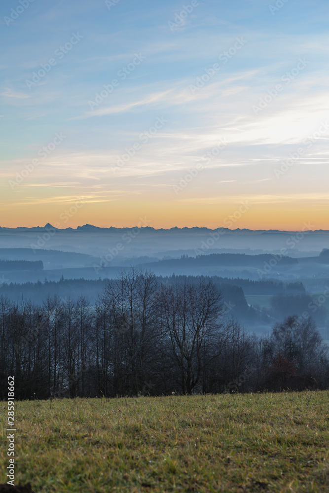 wide angle view of a frosty field and a foggy valley with an Austrian mountain range in the background wide angle view of a frosty field and a foggy valley with an Austrian mountain range in the background