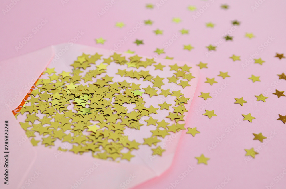 Holiday gentle concept: pink envelope and star confetti on pink background.