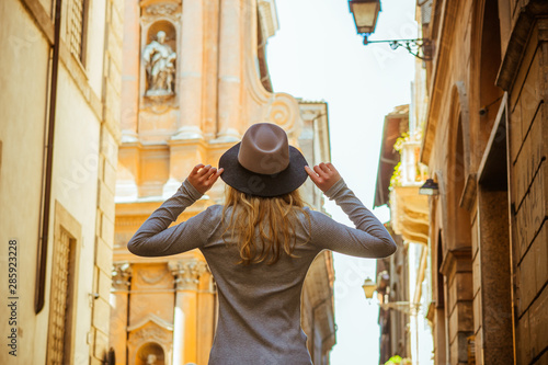 Back view of woman wearing greu sweater. Nice hat, hands up. Beautiful architecture. photo
