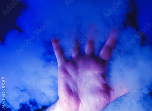 hand in blue smoke. Smoking and vaping photo