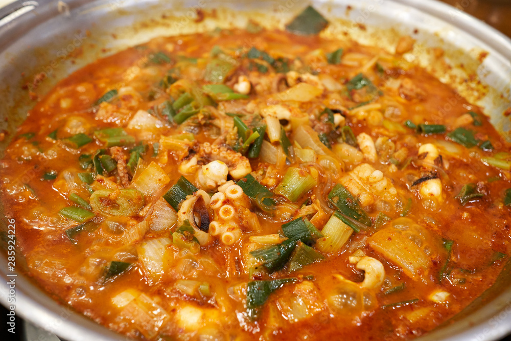 A close-up view of a spicy and hot cuisine with various sea food ingredients such as shrimp, small octopus, and tripe.
