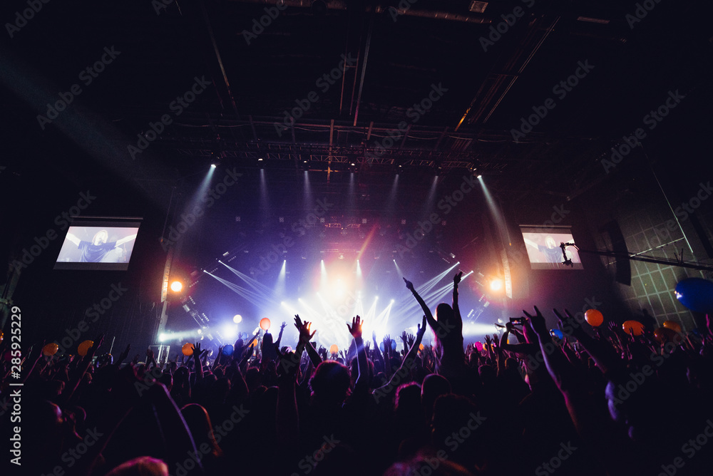 silhouettes of concert crowd in front of bright stage lights. Unrecognized people in crowd. Copy space background. Crowd of fans at music festive. Party in nightclub. Sold out concert. silhouettes of concert crowd in front of bright stage lights. Unrecognized people in crowd. Copy space background. Crowd of fans at music festive. Party in nightclub. Sold out concert.